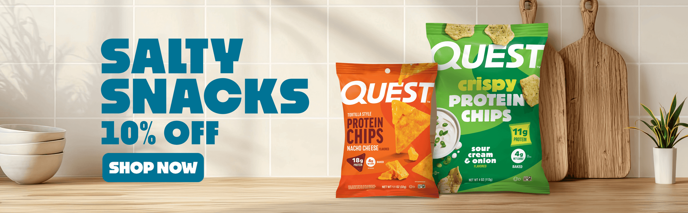 Text reads 'Salty Snacks 10% Off. Shop Now.' Advertisement featuring two bags of Quest protein chips on a wooden countertop.Relaxed kitchen setting with cutting boards and a plant in the background.