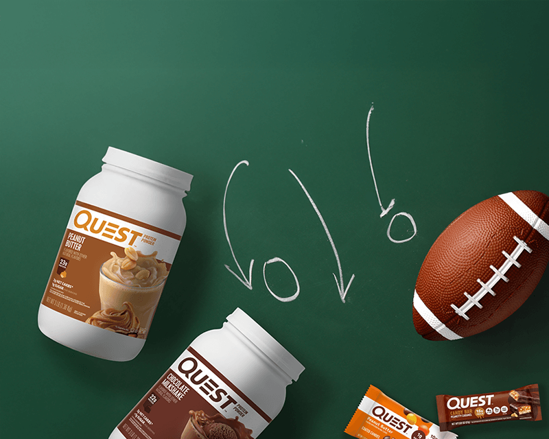 Protein powder jars and bars are styled as a football play on a green chalkboard, suggesting a sports theme. A football is on the right side.