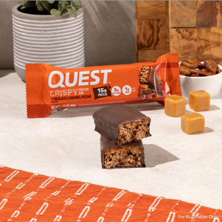 Quest Crispy protein bar with chocolate caramel pecan flavor on a white surface with an orange patterned mat.