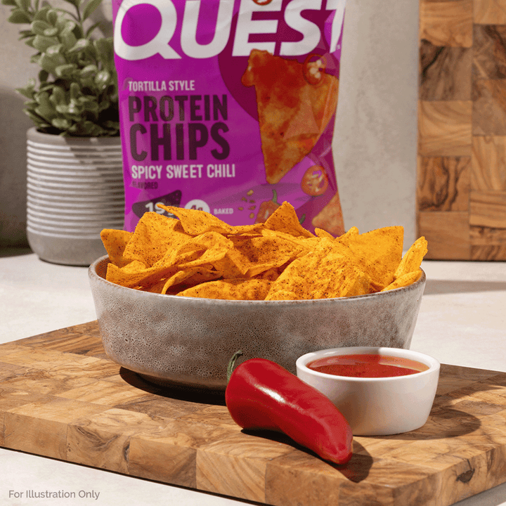 Bowl of Quest Spicy Sweet Chili Protein Chips served with dipping sauce and fresh chili peppers.