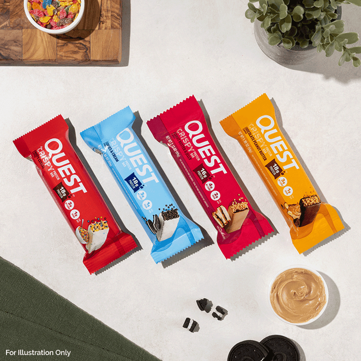 Four Quest protein bar packages on a white surface with a bowl of cereal and a plant in the background.