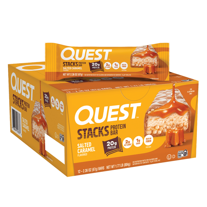 Box of Quest Stacks salted caramel protein bars with one bar on top. Packaging is mustard yellow featuring caramel visuals, highlighting 20g protein content.
