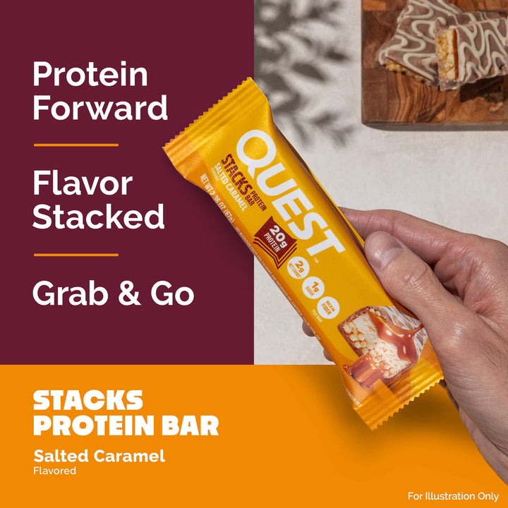A hand holds a yellow Quest Stacks Protein Bar with salted caramel flavor. Text highlights "Protein Forward," "Flavor Stacked," "Grab & Go." A wood board with sliced bars is visible in the background.