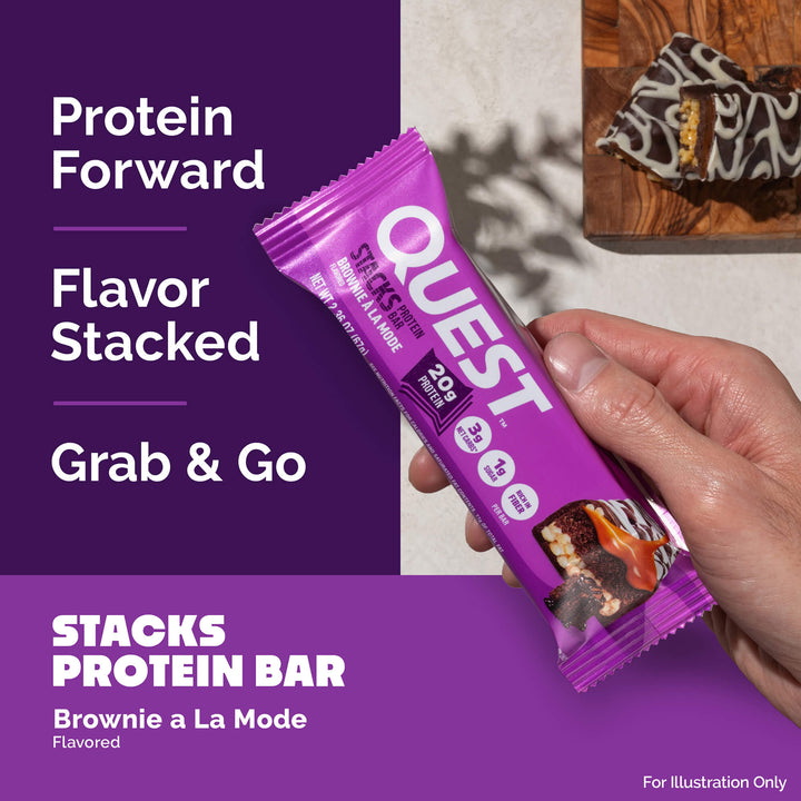 Hand holding a purple Quest protein bar with brownie image. Text reads: "Protein Forward, Flavor Stacked, Grab & Go." Brownie slice on wooden board.