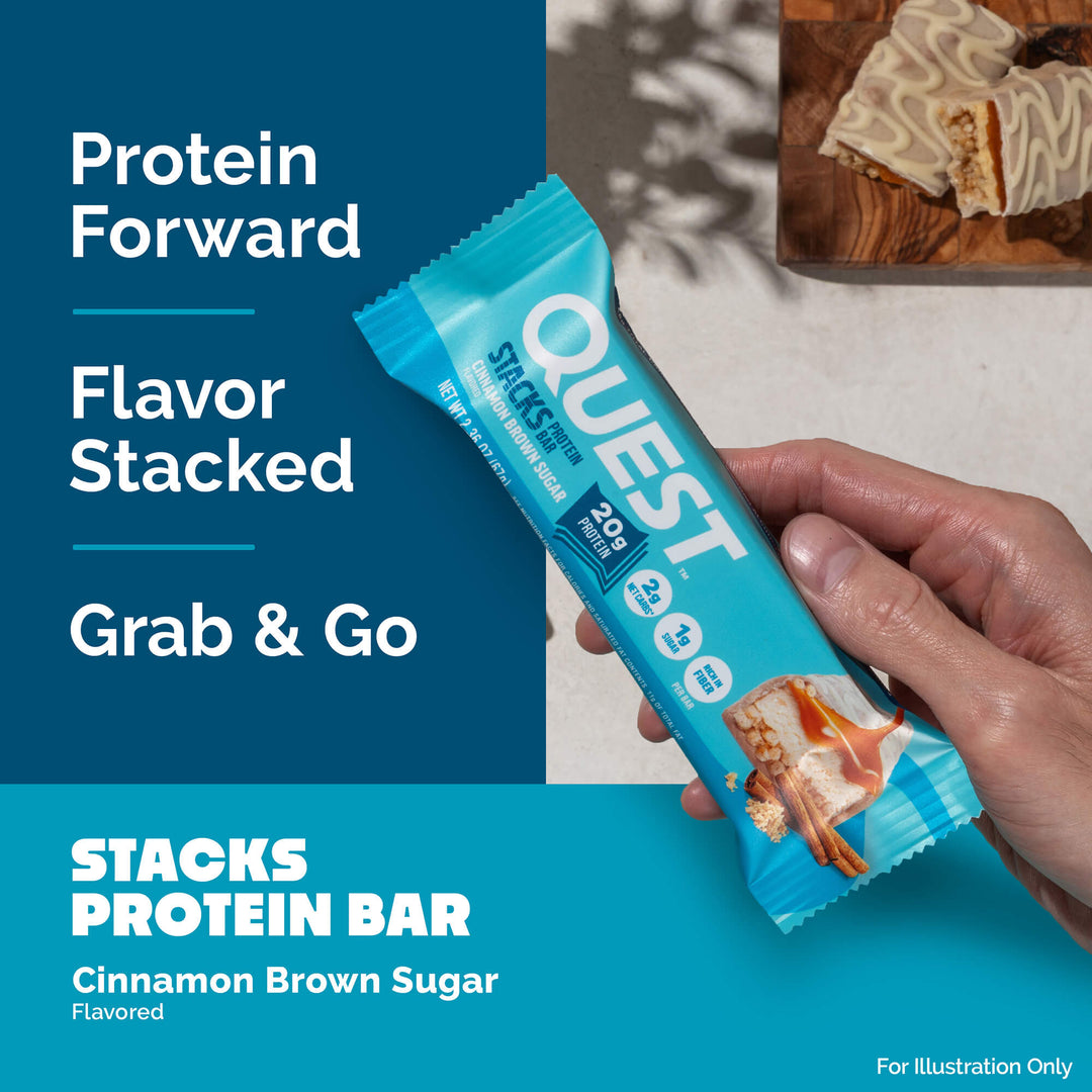 A person holds a Quest protein bar in blue packaging. Text reads "Protein Forward, Flavor Stacked, Grab & Go." Another bar is sliced on a wooden board.